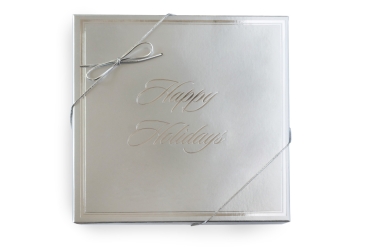 silver 4-part happy holidays gift box, tied with silver elastic ribbon. Photo taken on a white background.